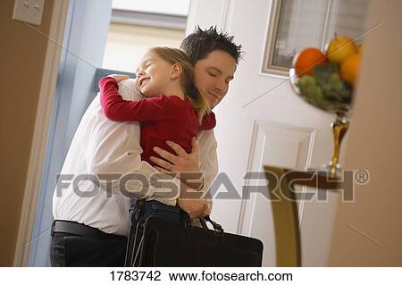 Stock Image - Daughter hugs father as he leaves for work. Fotosearch