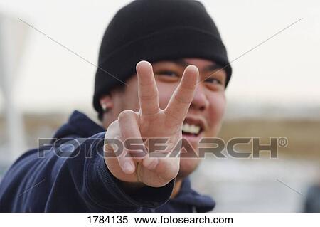 Stock Photography - Man with peace signal with fingers. Fotosearch