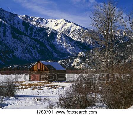 Stock Image - Old log barn in Rocky Mountains, winter. Fotosearch