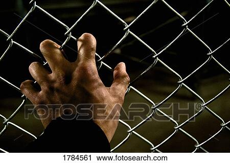 Stock Image - Single hand grasping a fence. Fotosearch