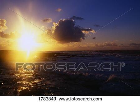 Stock Photo - Sunrise, dark clouds, ocean waves, Sand Beach Park. Fotosearch