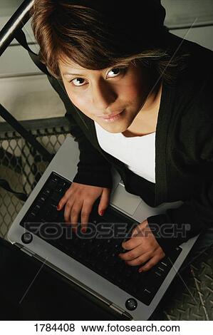 Stock Photo - Young adult using a laptop computer. Fotosearch
