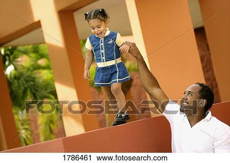 Stock Image - A father helps his small daughter. Fotosearch