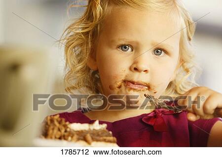 Stock Image - A young girl eating dessert. Fotosearch