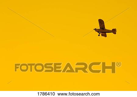 Stock Image - Airplane flying at sunset. Fotosearch