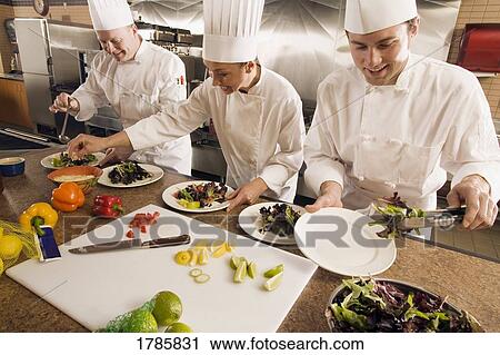Stock Image - Chef's assembling food in a kitchen. Fotosearch