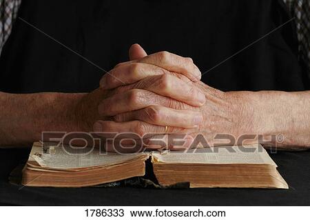 Stock Image - Closeup of senior's hands on Bible. Fotosearch