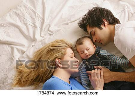 Family sleeping on bed from above View Large Photo Image Picture - Family sleeping on bed from above. Fotosearch