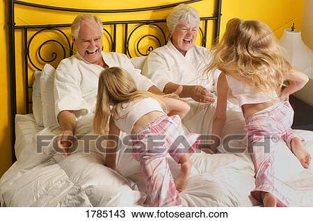 Grandparents playing with their granddaughters in a bed. View Large Photo Image Stock Image - Grandparents playing with their granddaughters in a bed.. Fotosearch