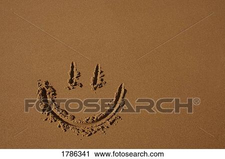 Stock Image - Happy face in the sand. Fotosearch