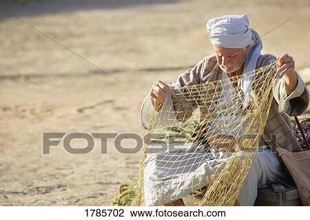 Man looking over fishing net View Large Photo Image Stock Image - Man looking over fishing net. Fotosearch