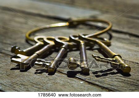 Stock Image - Old-fashioned keys laying on wood flooring. Fotosearch