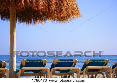 Palm hut offering shade on tropical beach View Large Photo Image Stock Image - Palm hut offering shade on tropical beach. Fotosearch