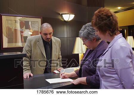 Two women checking into hotel View Large Photo Image Stock Photograph - Two women checking into hotel. Fotosearch