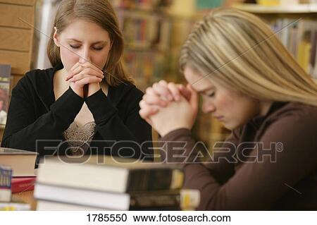 Two women praying in library View Large Photo Image Stock Image - Two women praying in library. Fotosearch