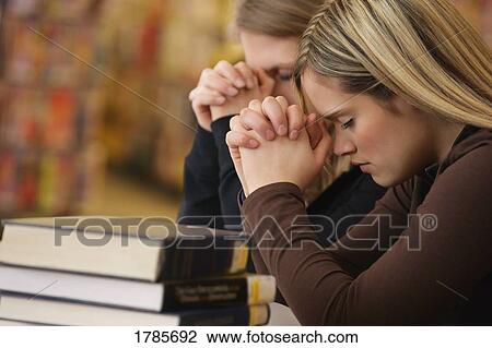 Two women praying in library View Large Photo Image Stock Image - Two women praying in library. Fotosearch