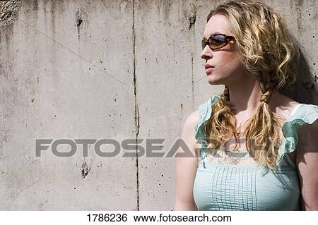 Stock Photograph - Woman in sunglasses against wall. Fotosearch