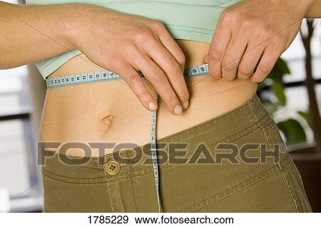 Woman measuring her waist View Large Photo Image Stock Photo - Woman measuring her waist. Fotosearch