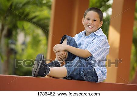 Young boy sitting balanced on a wall View Large Photo Image Stock Image - Young boy sitting balanced on a wall. Fotosearch