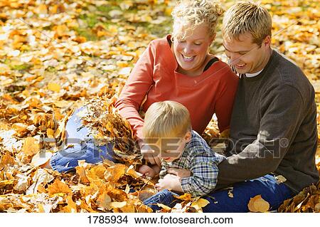 Young family playing in leaves View Large Photo Image Picture - Young family playing in leaves. Fotosearch