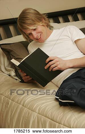 Young man reading in his room View Large Photo Image Stock Photography - Young man reading in his room. Fotosearch