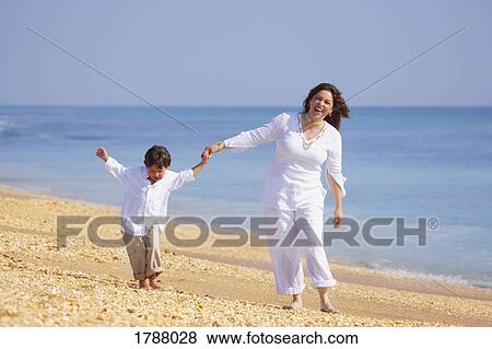 Stock Photo - A mother and son walk along the beach. Fotosearch