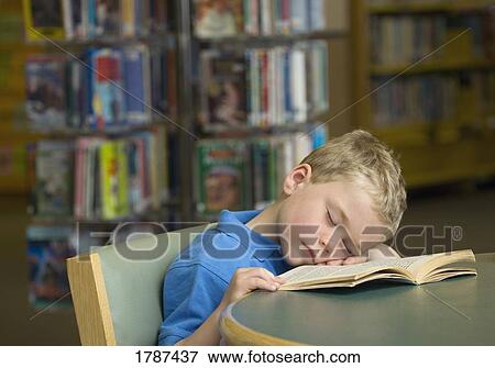 A young boy falls asleep reading at the library View Large Photo Image Stock Photo - A young boy falls asleep reading at the library. Fotosearch