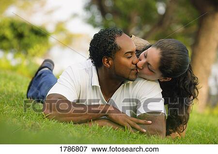 Stock Photo - Couple kissing in the grass. Fotosearch