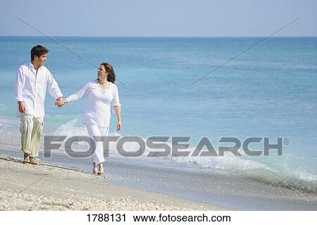 Stock Image - Couple strolling on a beach. Fotosearch