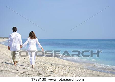Stock Image - Couple walking on beach. Fotosearch