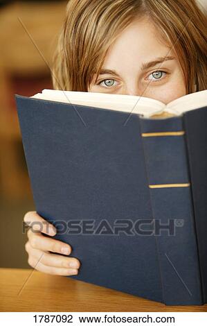 Girl peering over the top of a book View Large Photo Image Stock Image - Girl peering over the top of a book. Fotosearch