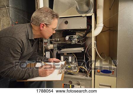 Picture - Man inspecting furnace. Fotosearch
