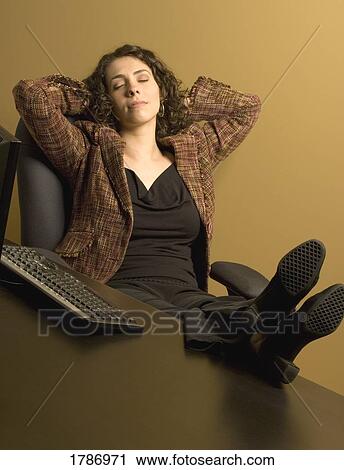 Stock Image - Woman resting at her desk. Fotosearch