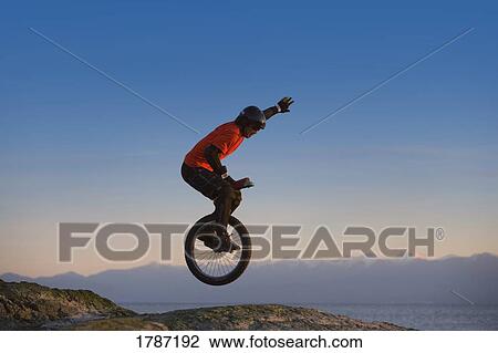 Young man mountain unicycling View Large Photo Image Stock Image - Young man mountain unicycling. Fotosearch