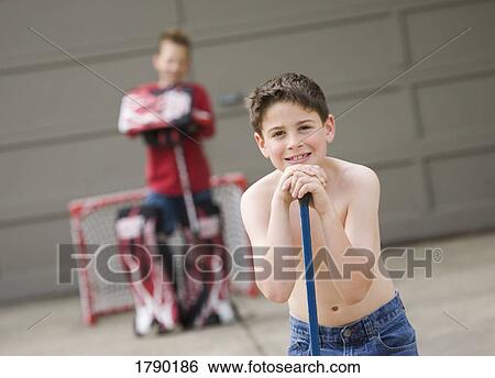 Stock Photograph - A boy rests on his hockey stick. Fotosearch