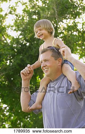 A little girl rides on her fathers shoulders View Large Photo Image Stock Photography - A little girl rides on her fathers shoulders. Fotosearch