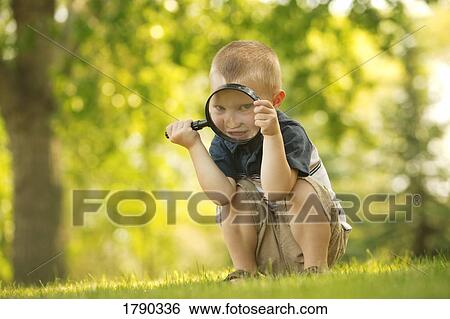 Stock Photograph - Boy looking through magnifying glass. Fotosearch