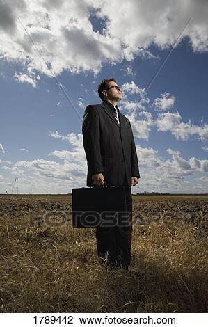 Stock Image - Business man in a field. Fotosearch
