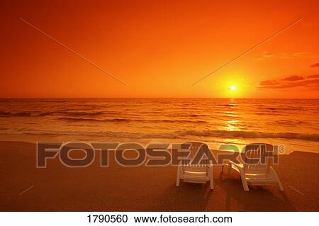 Stock Image - Chairs on a sunset beach. Fotosearch