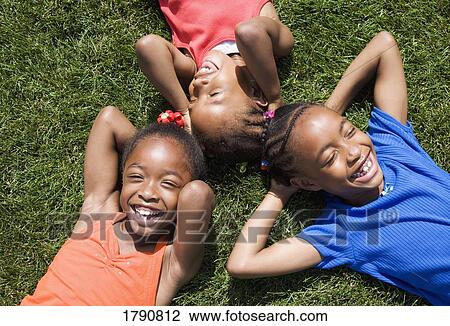 Children laying together in grass View Large Photo Image Stock Image - Children laying together in grass. Fotosearch
