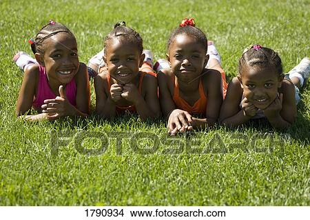 Picture - Four girls laying on the grass. Fotosearch