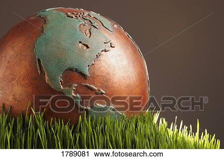 Stock Image - Globe set on green grass. Fotosearch