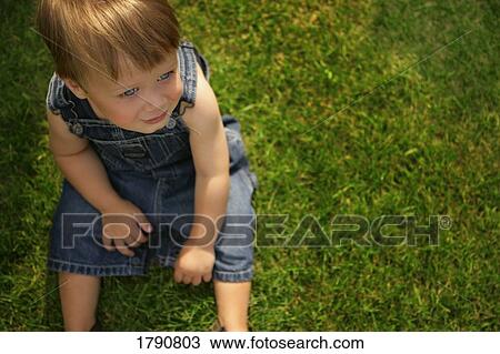Stock Image - Little boy sitting on grass. Fotosearch
