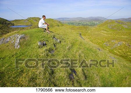Man sitting on top of a hill View Large Photo Image Stock Photograph - Man sitting on top of a hill. Fotosearch