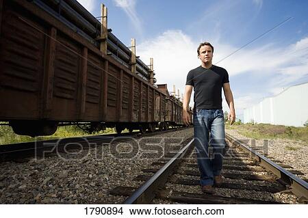 Man walking on railroad tracks View Large Photo Image Picture - Man walking on railroad tracks. Fotosearch