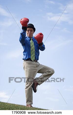 Man wearing boxing gloves and derby hat standing on one leg View Large Photo Image Stock Photo - Man wearing boxing gloves and derby hat standing on one leg. Fotosearch