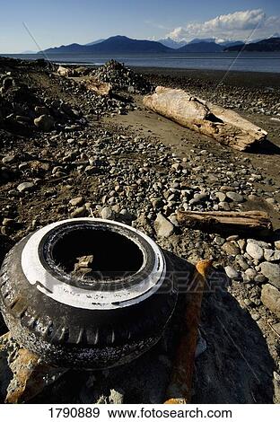 Stock Photo - Old tire and rusty waste on beach. Fotosearch