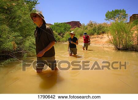 Stock Image - People wading through a creek. Fotosearch