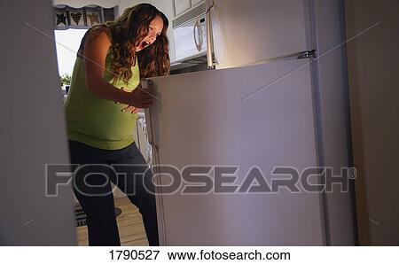 Stock Photo - Pregnant woman looking in refrigerator. Fotosearch