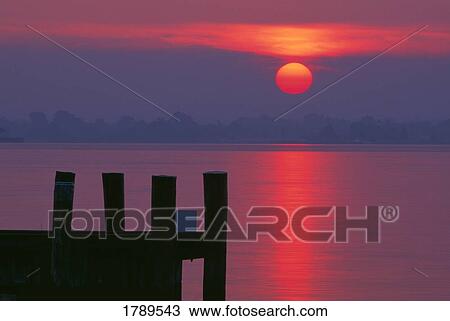 Stock Image - Sunrise overlooking pier. Fotosearch